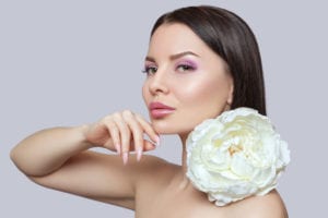 Portrait of a beautiful happy woman with clean skin and beautiful make-up. Beautiful eyes close up. She holds a white peony near her face.Cosmetology skin care and make-up concept